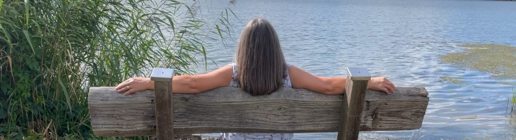 Anja sitzt auf einer Bank am Wasser